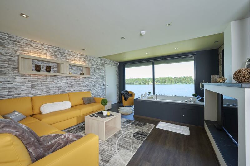 Pallazy : salon avec canapé d’angle, jacuzzi et vue sur le lac
